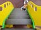 Cute Caucasian baby climbs the yellow stairs on a children playground. on the floor on a rubberized safe cover is the