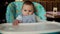 Cute caucasian baby girl sitting serious and calm on a high chair in cafe 4k