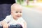 Cute caucasian blond curious baby boy sitting in stroller , smiling, looking and aspiring to something outdoor at city park.