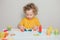 Cute Caucasian blond curly baby boy child playing with sensor kinetic toy playdough. Hand brain development activity for young