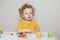Cute Caucasian blond curly baby boy child playing with sensor kinetic toy playdough. Hand brain development activity for young