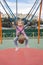 Cute caucasian child girl swinging on a swing on a children`s playground