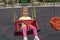 Cute caucasian child swings on swing, with interested and surprised expression.