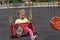 Cute caucasian child swings on swing, laughing and crying with happy expression