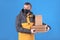 Cute caucasian courier and food delivery man in black mask and rubber gloves in yellow jacket and thermal bag behind his
