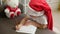 cute caucasian girl 5-6 years old in a santa hat writes a letter to santa claus