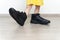 Cute caucasian little girl in a yellow dress posing in huge men`s boots against a gray wall, mock up with copy space