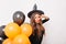 Cute caucasian model enjoying halloween photoshoot on white background. Debonair girl in witch hat holding black and