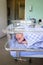 Cute Caucasian newborn infant sleeps in glass hospital bed under blanket