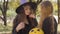 Cute caucasian redhead girl dressed in witch costume talking to her blonde friend. Two little friends discussing the