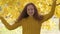 Cute caucasian redhead girl posing on the background of yellow leaves. Child with long curly hair in mustard sweater