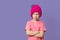 cute caucasian toddler girl in a knitted hat on a pink background, cowardly child, displeasure emotion