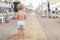 Cute caucasian toodler boy walking alone on sandy beach between chaise-lounge. Adorable happy child having fun playing