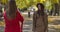 Cute Caucasian woman in elegant brown clothes and hat posing for her female friend on the background of autumn park