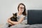 Cute caucasian young woman in eyeglasses relaxing resting on comfortable bed with cute pet cat watching remote education webinar