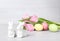 Cute ceramic bunnies, Easter eggs and spring tulips on table against light background