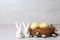 Cute ceramic bunnies near decorative nest with Easter eggs on table