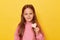 Cute charming smiling delighted brown haired little girl wearing pink sweatshirt isolated over yellow background showing tine