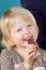 Cute cheeky little blond girl eating a sweet