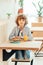 cute cheerful curly boy sitting in cafe in cafe with piece of cake