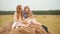 Cute cheerful girls sitting on haystack and reading book