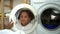 Cute child behind washing machine glass talk to mom. Mom and daughter on domestic household