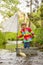 Cute child, boy in colorful jacket, playing with boat and ducks on a little river, sailing and boating. Kid having fun, childhood