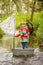 Cute child, boy in colorful jacket, playing with boat and ducks on a little river, sailing and boating. Kid having fun, childhood