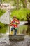 Cute child, boy in colorful jacket, playing with boat and ducks on a little river, sailing and boating. Kid having fun, childhood