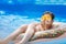 Cute child boy on funny inflatable donut float ring in swimming pool with oranges. Teenager learning to swim