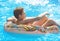 Cute child boy on funny inflatable donut float ring in swimming pool with oranges. Teenager learning to swim, have fun outdoor