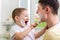 Cute child boy shaving father in bathroom