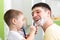 Cute child boy shaving his father in bathroom