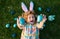 Cute child bunny wear rabbit ears in garden, Happy Easter day. Bunny boy, funny outdoor portrait. Hunting eggs and