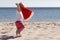 Cute child celebrating Christmas and New Year holidays in the Caribbean beach dressed as Santa.