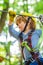 Cute child in climbing safety equipment in a tree house or in a rope park climbs the rope. Happy little child climbing