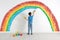 Cute child drawing rainbow on white wall