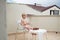 Cute child eats strawberries in summer sitting on the terrace on the background of the roofs