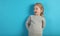 Cute child girl in astonishment looks to the side on  blue background
