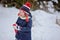 Cute child girl in christmas knitted hat walking in winter snowy garden