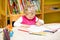 Cute child girl drawing with colorful pencils in preschool at table in kindergarten