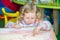 Cute child girl drawing draws developing sand in preschool at table in kindergarten