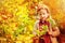 Cute child girl gathering apples from tree in sunny autumn garden