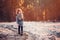 Cute child girl in grey knitted coat plays on the walk in winter forest