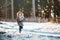 Cute child girl in grey knitted coat plays on the walk in winter forest