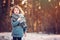 Cute child girl in grey knitted coat plays on the walk in winter forest