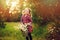 Cute child girl picking flowers outdoor on summer field, cozy mood