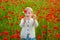 Cute child girl in poppy field. Little girl play outdoor in poppy field. Lovely child on poppies background. Kids near