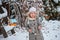 Cute child girl puts seeds in bird feeder in winter snowy garden