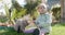 Cute child girl sitting on lawn and feeding cats in spring backyard garden